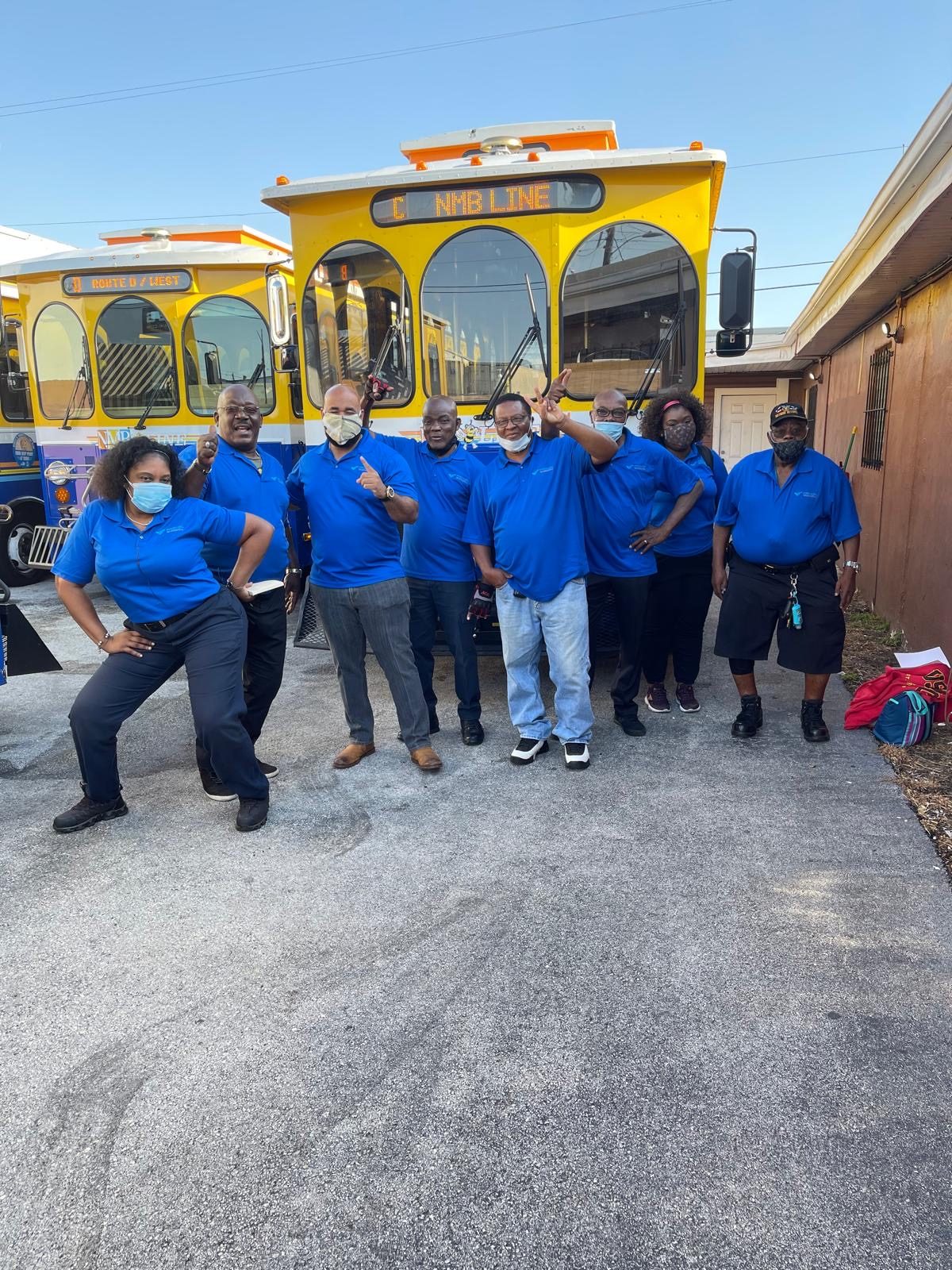 Shuttle drivers in uniform beside their bus